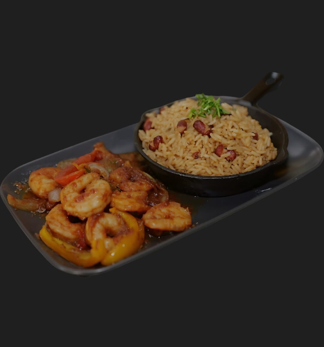 Shrimp with peppers and onions served with a skillet of seasoned rice and beans