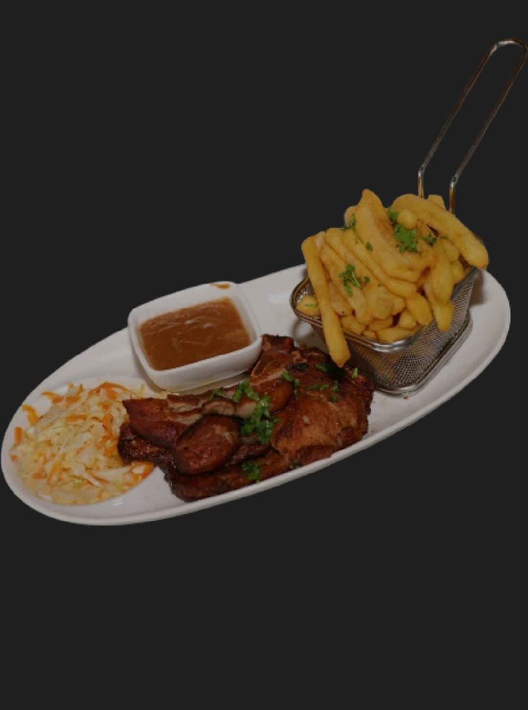 Grilled pork served on an oval plate with fries, coleslaw and sauce