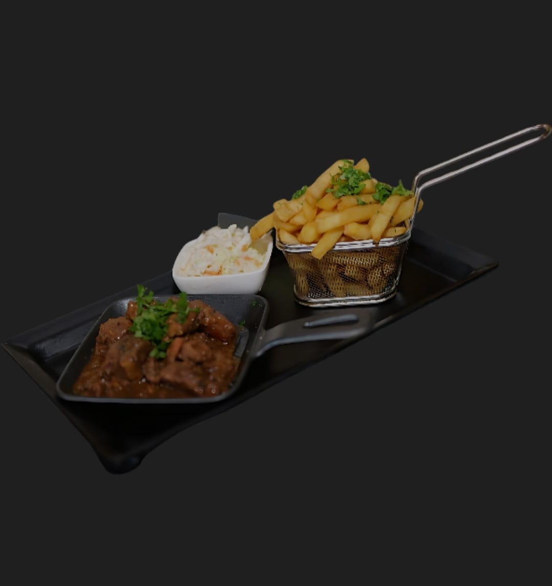 Stewed meat in a dark dish served with a basket of fries and coleslaw