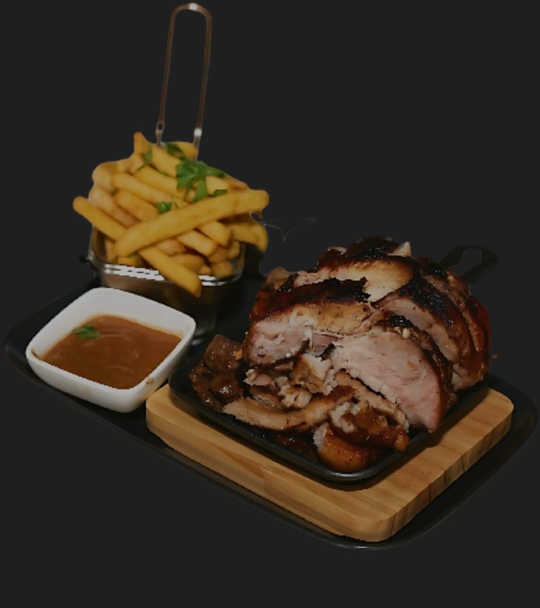 Sliced roast pork on a wooden board with fries and a bowl of sauce