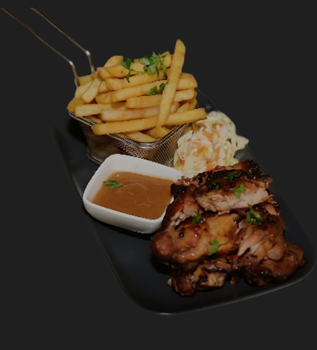 Grilled chicken served with a basket of fries, coleslaw and a bowl of sauce at Kos Bon So